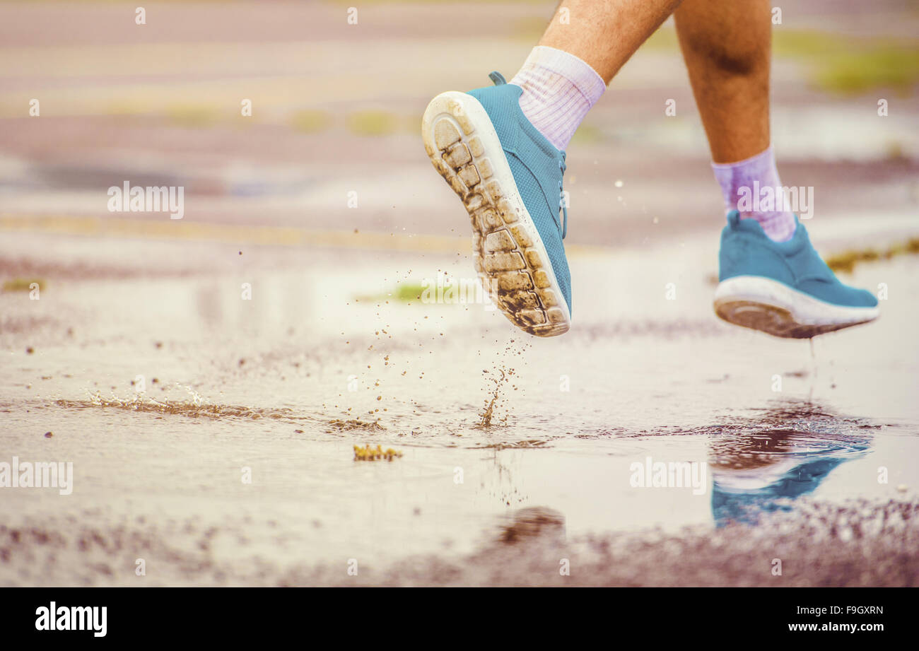 Junger Mann Joggen auf Asphalt bei Regenwetter Stockfoto