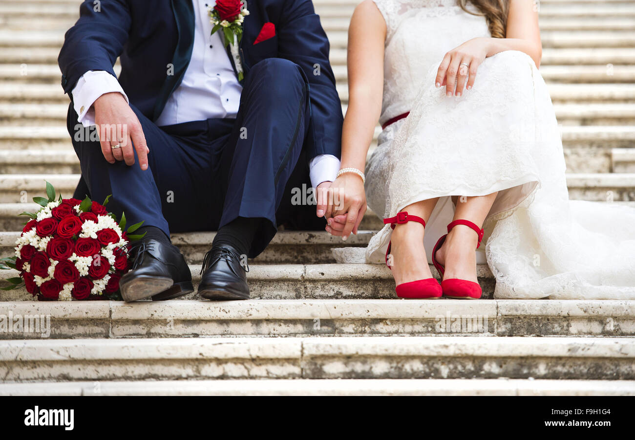 Nicht erkennbare junge Hochzeit paar Hand in Hand, wie sie genießen Sie romantische Stunden draußen auf der Treppe Stockfoto