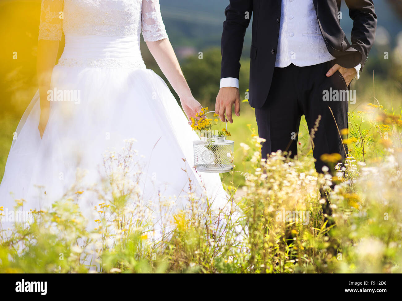 Nicht erkennbare junge Hochzeit paar Hand in Hand, wie sie genießen Sie romantische Momente außerhalb auf einer Sommerwiese Stockfoto