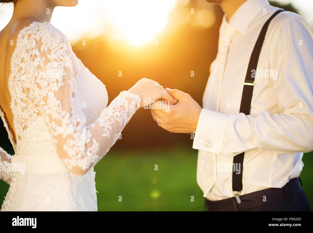 Junge Paar Hand in Hand Hochzeit, genießen sie romantische Momente außerhalb auf einer Sommerwiese Stockfoto