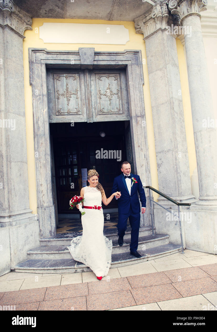 Braut und Bräutigam aus der Kirche Hand in Hand gehen Stockfoto