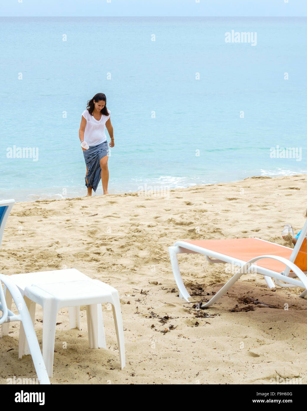 Eine dunkelhaarige kaukasischen Frau in einem langen Rock kommt aus dem Wasser an den Strand auf St. Croix, Amerikanische Jungferninseln. Stockfoto
