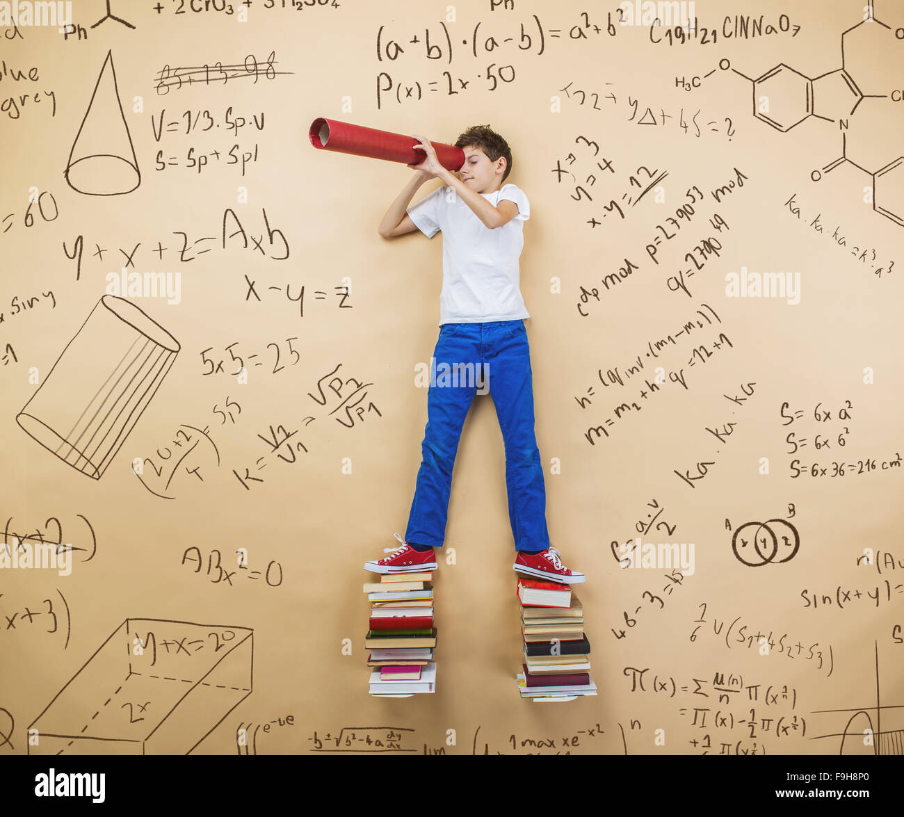 Niedliche kleine Junge lernen spielerisch im Frot an einer großen Tafel. Studio auf Beige Hintergrund gedreht. Stockfoto