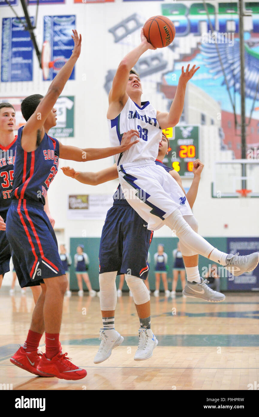 Ein High-School-Forward verlässt den Boden über die Farbe und zwischen zwei Verteidigern auf der Suche nach Punkten. Stockfoto