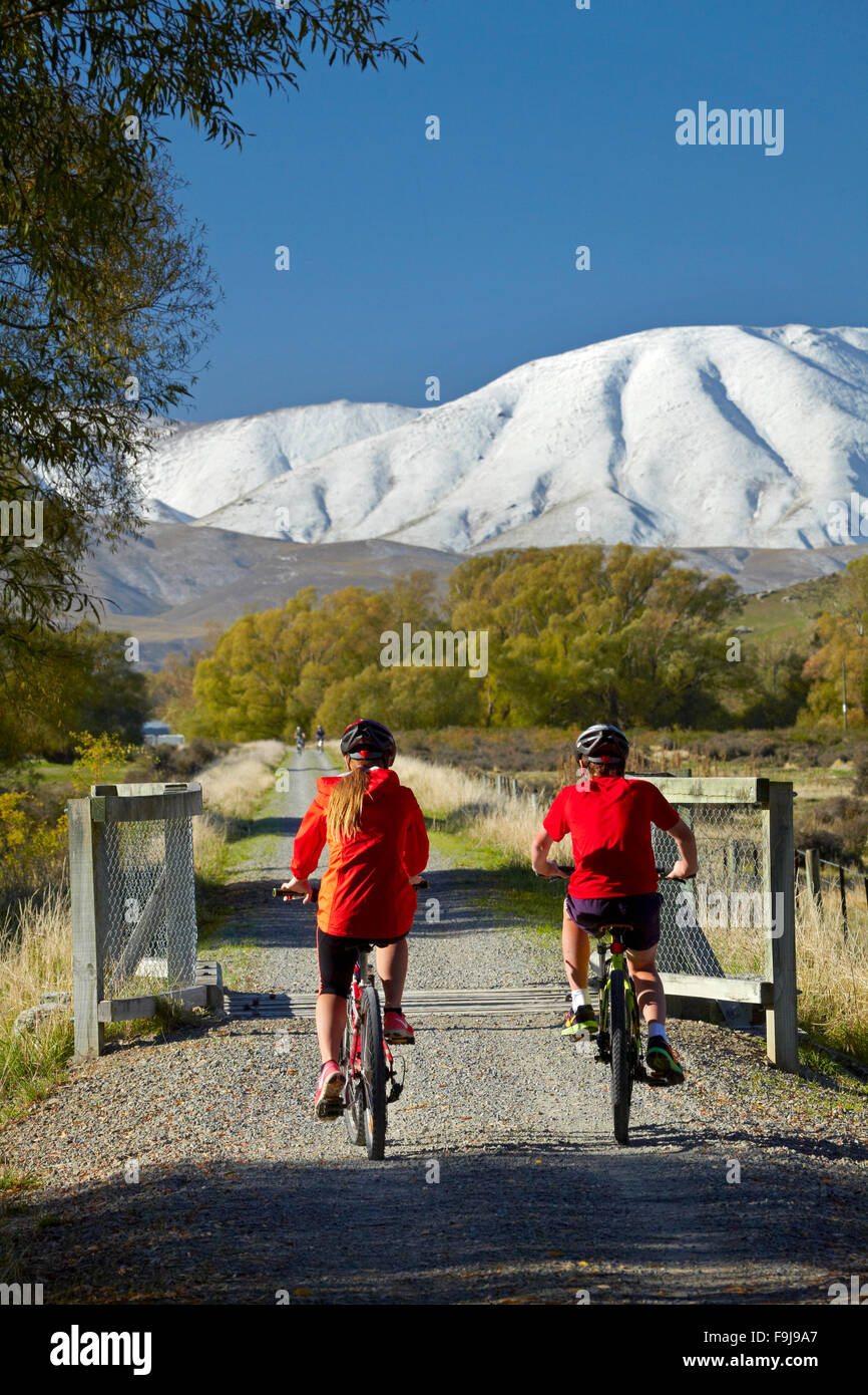 Radfahrer auf Otago Central Rail Trail im Ida-Tal und Schnee auf Ida Range, Central Otago, Südinsel, Neuseeland Stockfoto