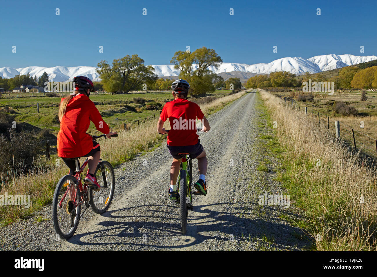 Radfahrer auf Otago Central Rail Trail im Ida-Tal und Schnee auf Ida Range, Central Otago, Südinsel, Neuseeland Stockfoto