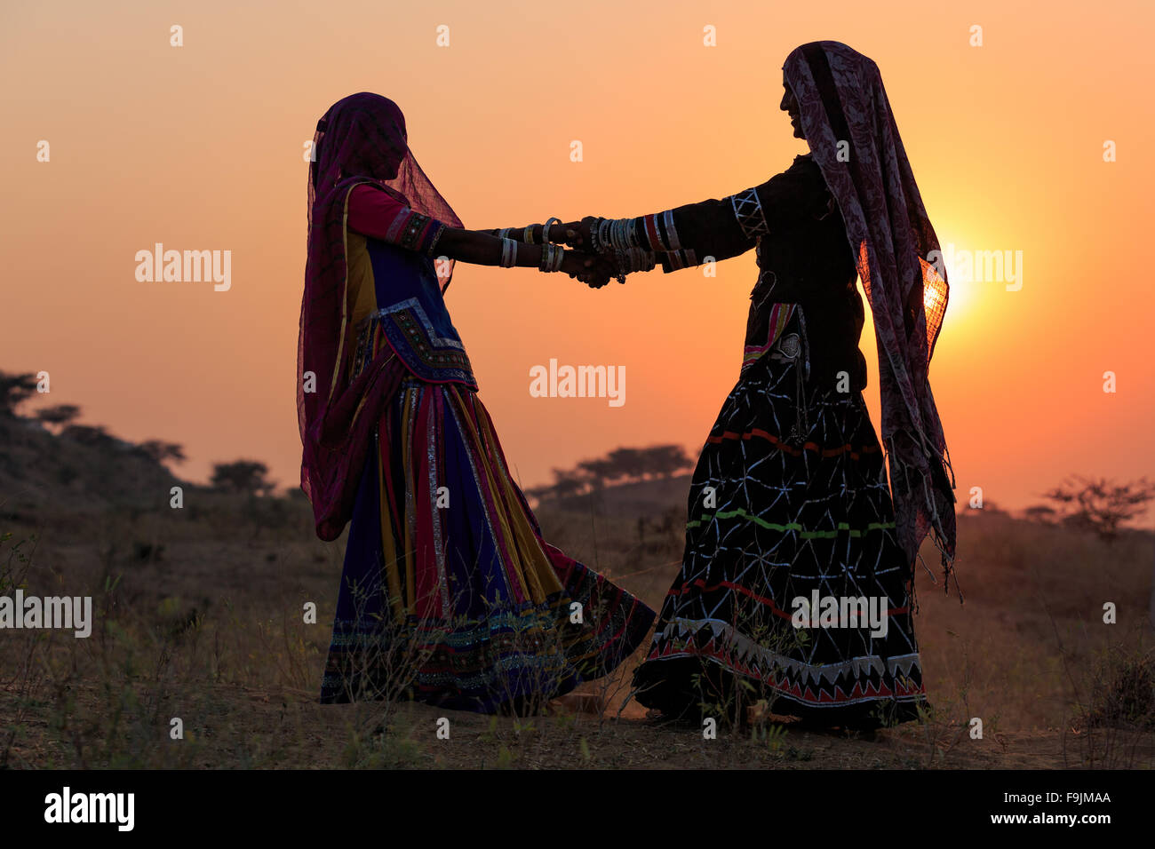 Silhouetten der beiden Frauen tanzen einen traditionellen Tanz bei Sonnenuntergang, Pushkar Camel Fair, Pushkar, Rajasthan, Indien Stockfoto