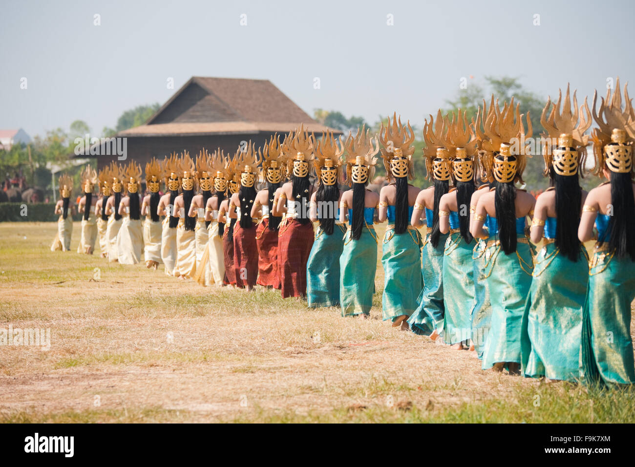 Linie von traditionell gekleideten Thai Tänzern zu Fuß auf dem Feld bei der jährlichen Surin Elephant Roundup Stockfoto
