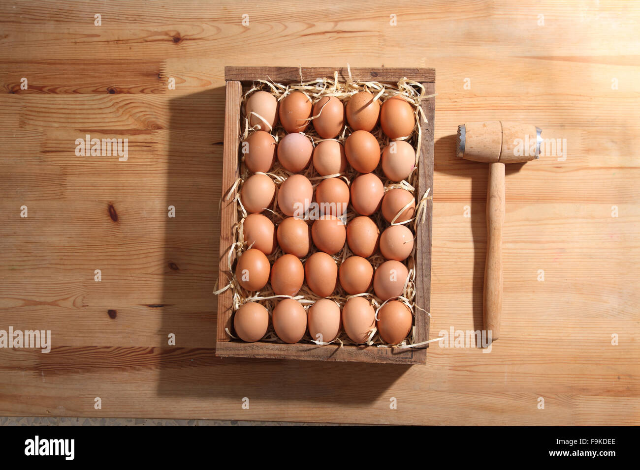 Haufen von frischen braunen Eiern und etwas Stroh in einer Holzkiste Stockfoto