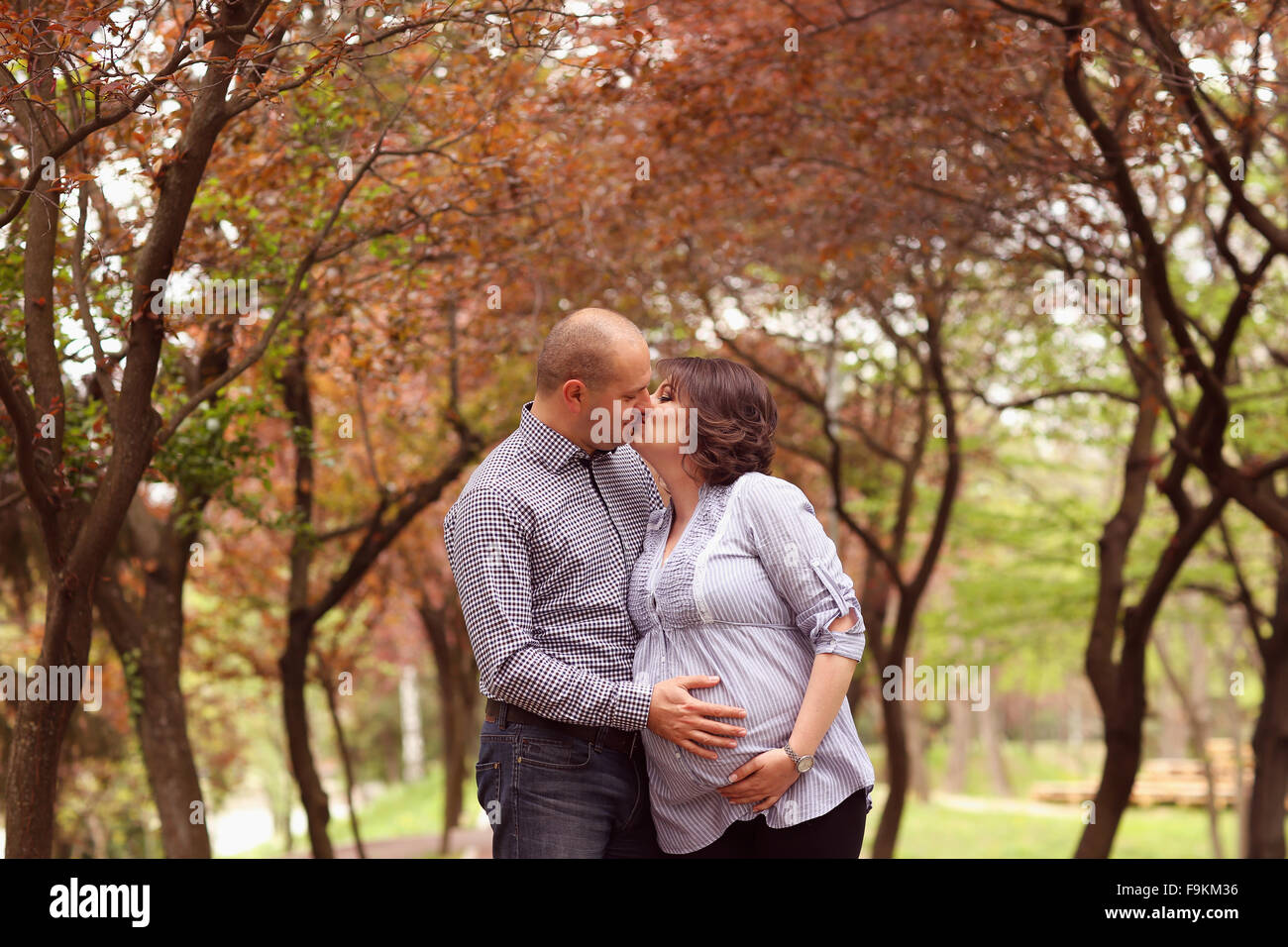Glücklich und junge schwangere paar umarmen in der Natur Stockfoto