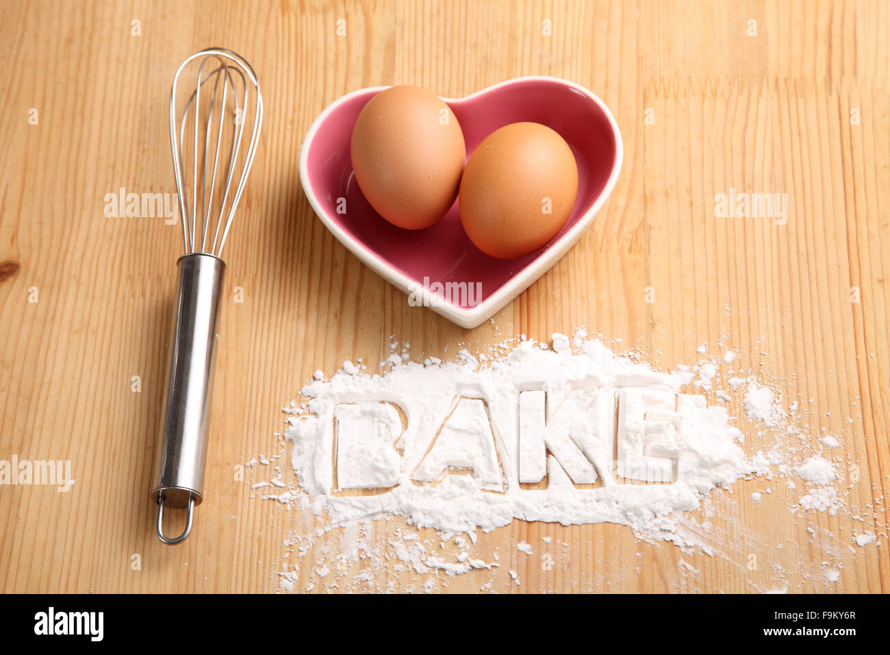 Backen, Konzept, Hand Schneebesen und Eiern in einem Herz-Form-container Stockfoto