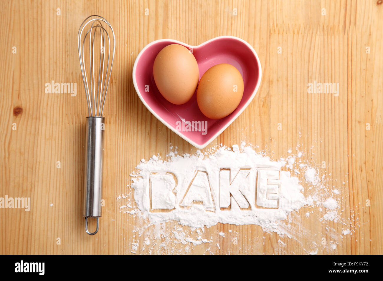 Backen, Konzept, Hand Schneebesen und Eiern in einem Herz-Form-container Stockfoto