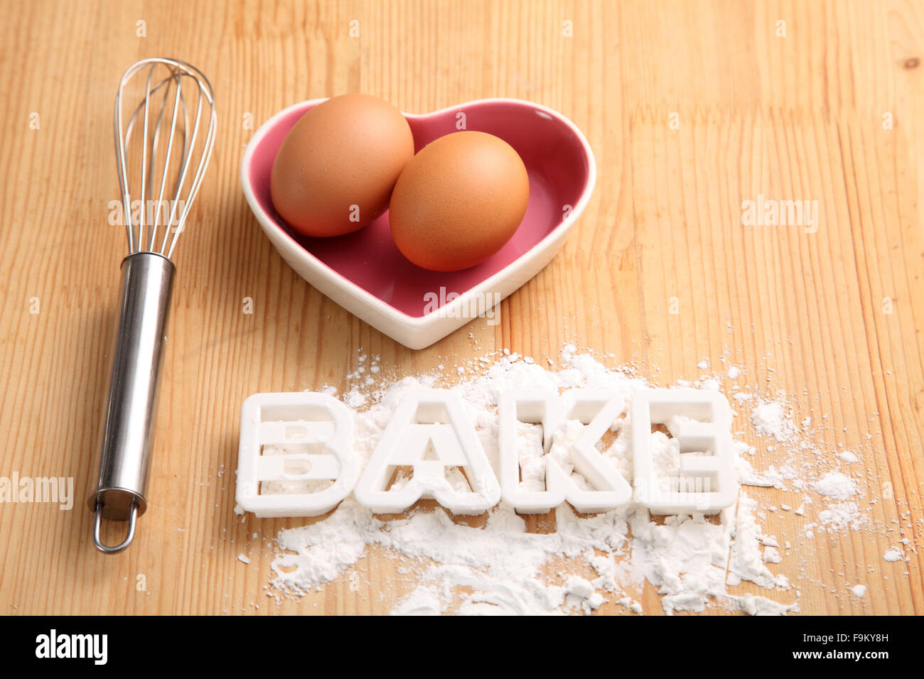 Backen, Konzept, Hand Schneebesen und Eiern in einem Herz-Form-container Stockfoto
