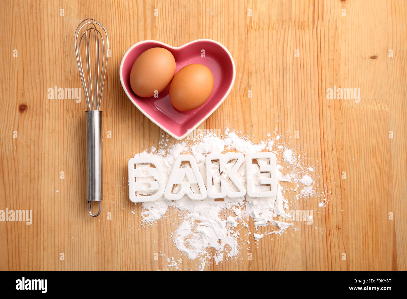 Backen, Konzept, Hand Schneebesen und Eiern in einem Herz-Form-container Stockfoto