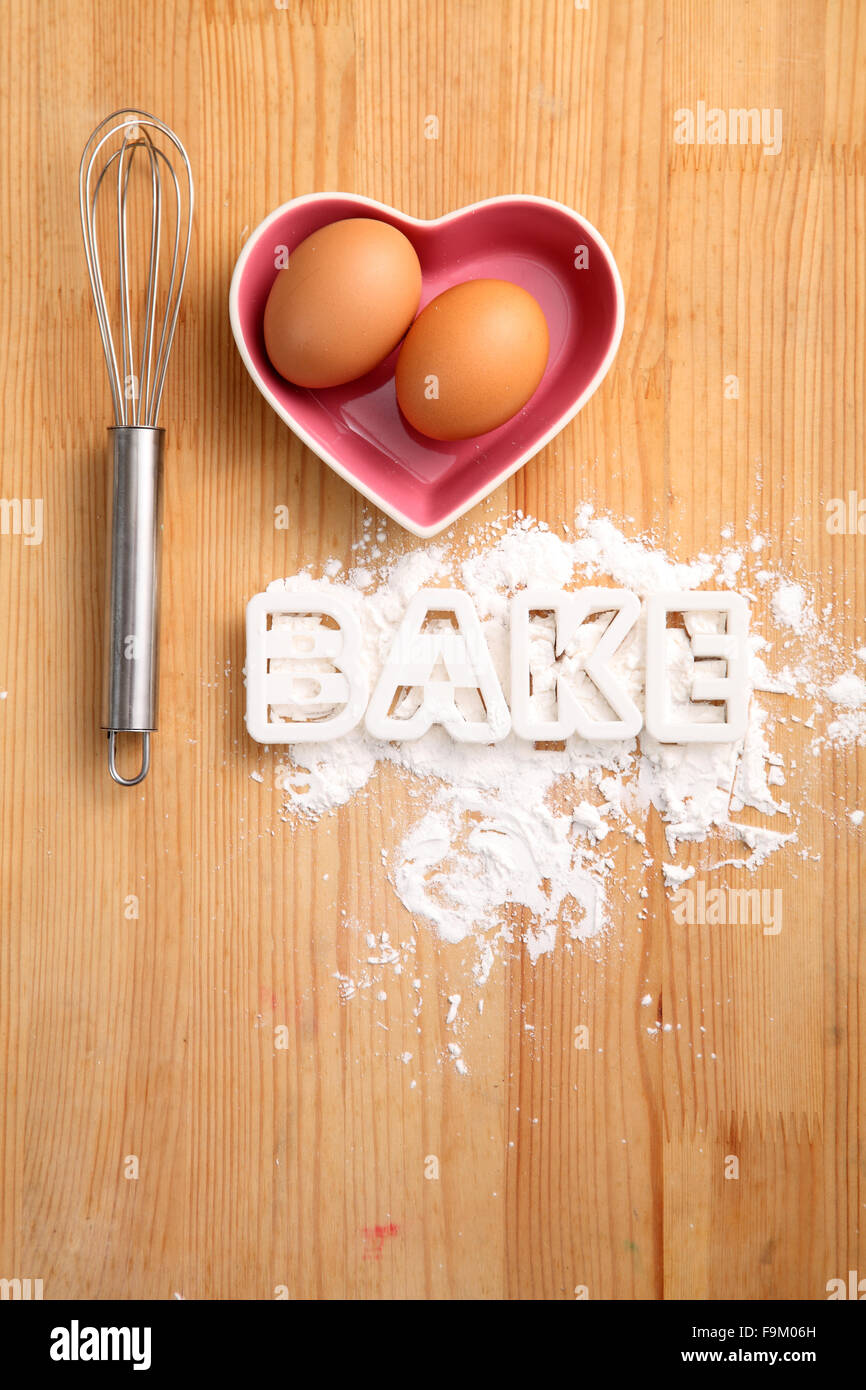 Backen, Konzept, Hand Schneebesen und Eiern in einem Herz-Form-container Stockfoto