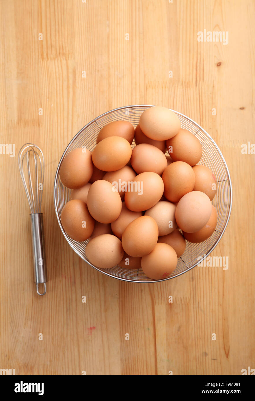 Eiern in Korb und Hand Schneebesen auf weißem Hintergrund Stockfoto