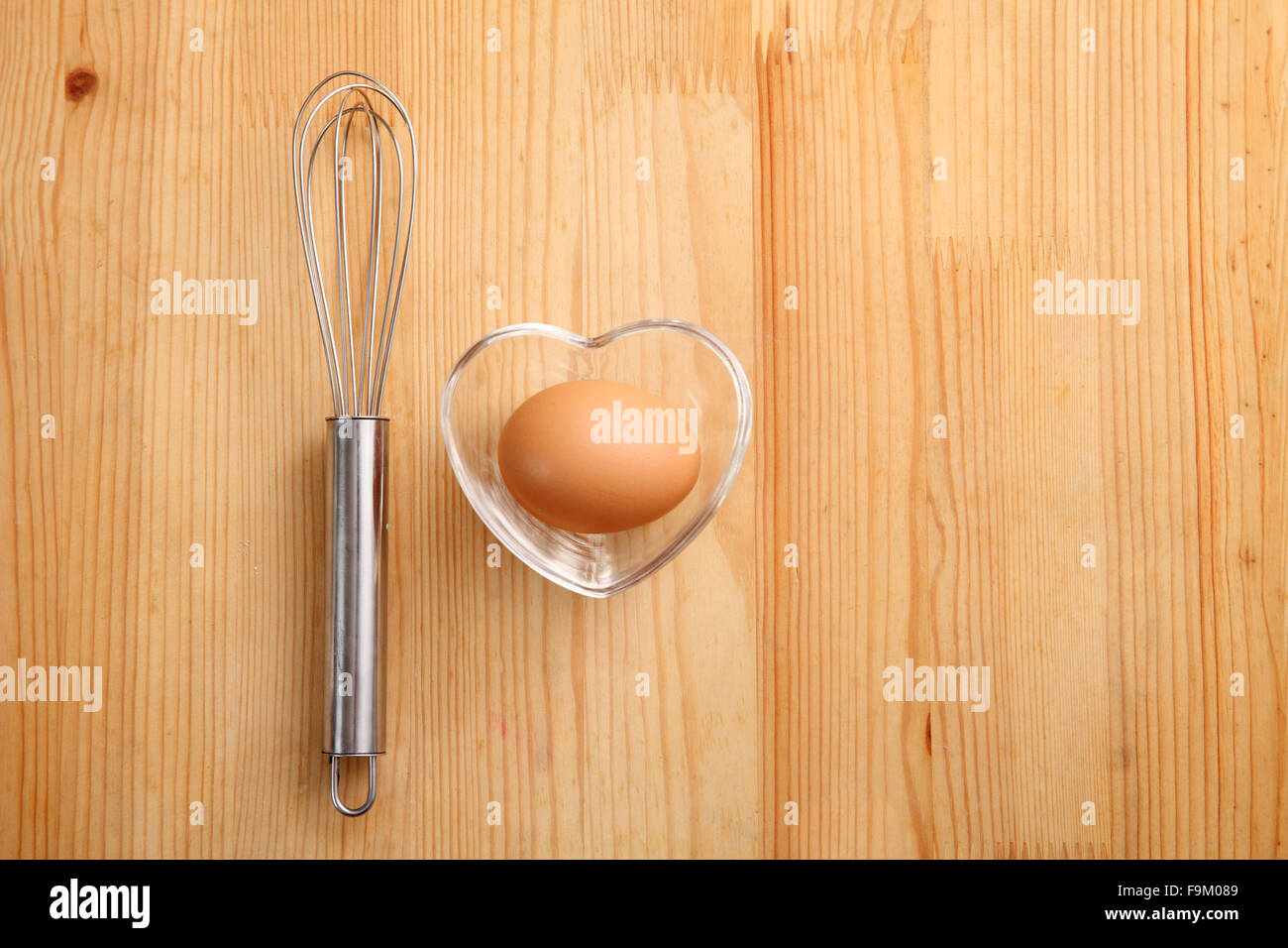 Backen Konzept Hand Schneebesen neben Ei in einem Herz-Form-container Stockfoto