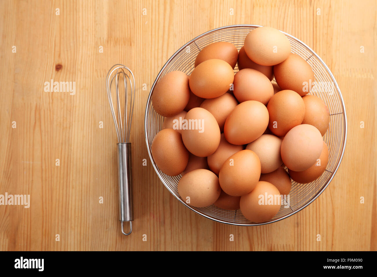 Eiern in Korb und Hand Schneebesen auf weißem Hintergrund Stockfoto