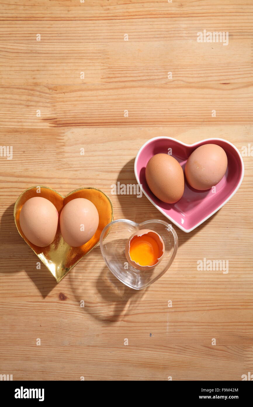 Braunen Eiern in Herz-Form transparent Schüssel auf hölzernen Hintergrund. Stockfoto