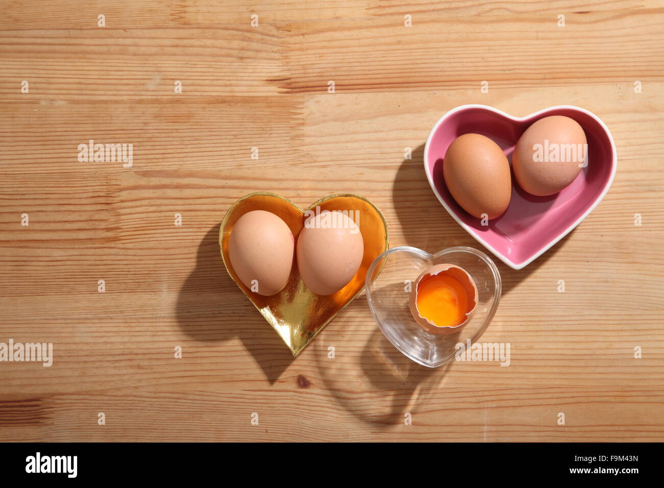 Braunen Eiern in Herz-Form transparent Schüssel auf hölzernen Hintergrund. Stockfoto