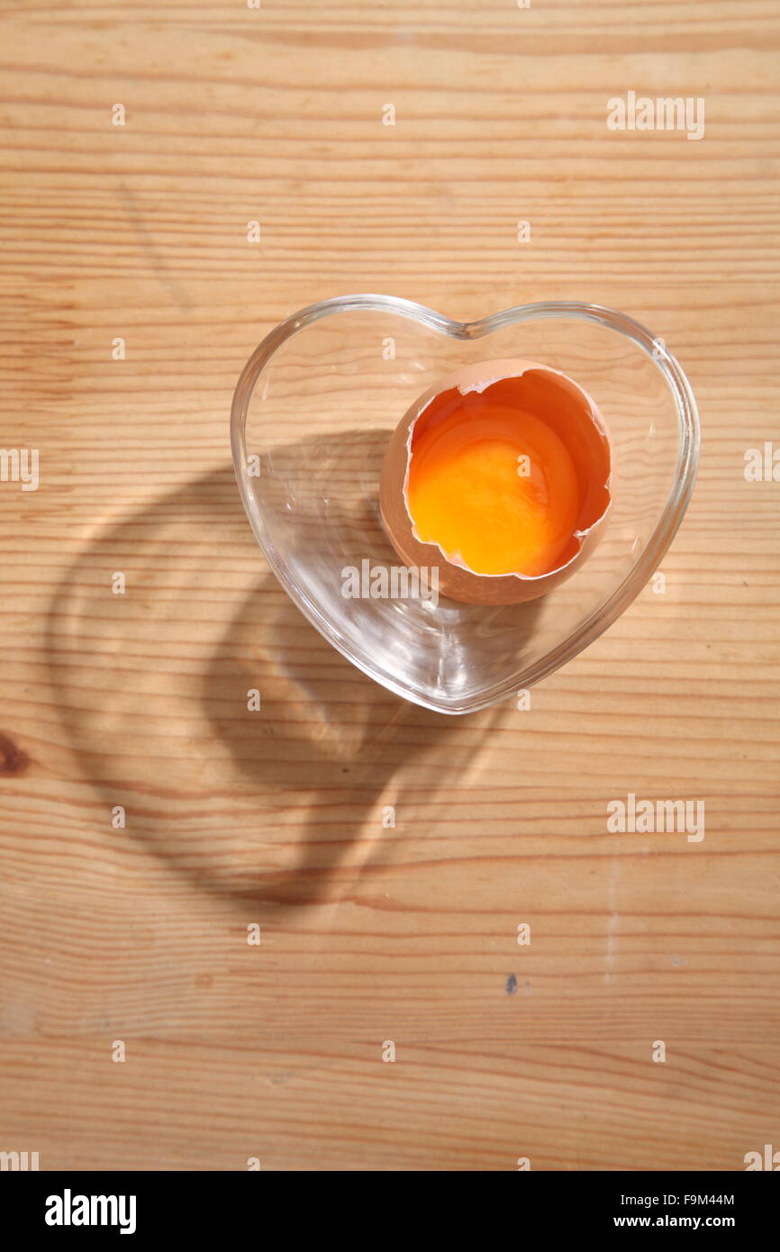 Braunen Eiern in Herz-Form transparent Schüssel auf hölzernen Hintergrund. Stockfoto