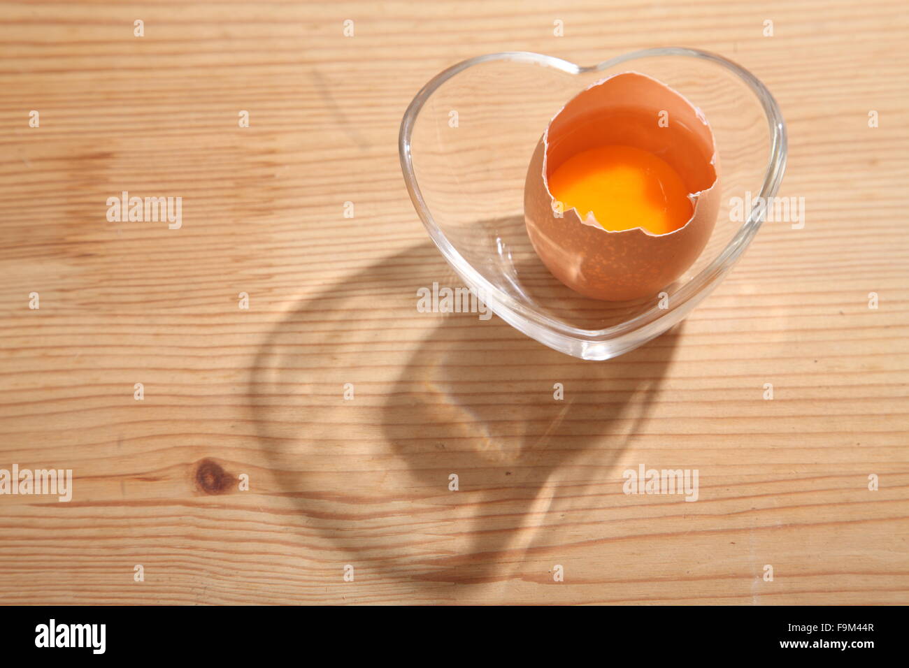 Braunen Eiern in Herz-Form transparent Schüssel auf hölzernen Hintergrund. Stockfoto