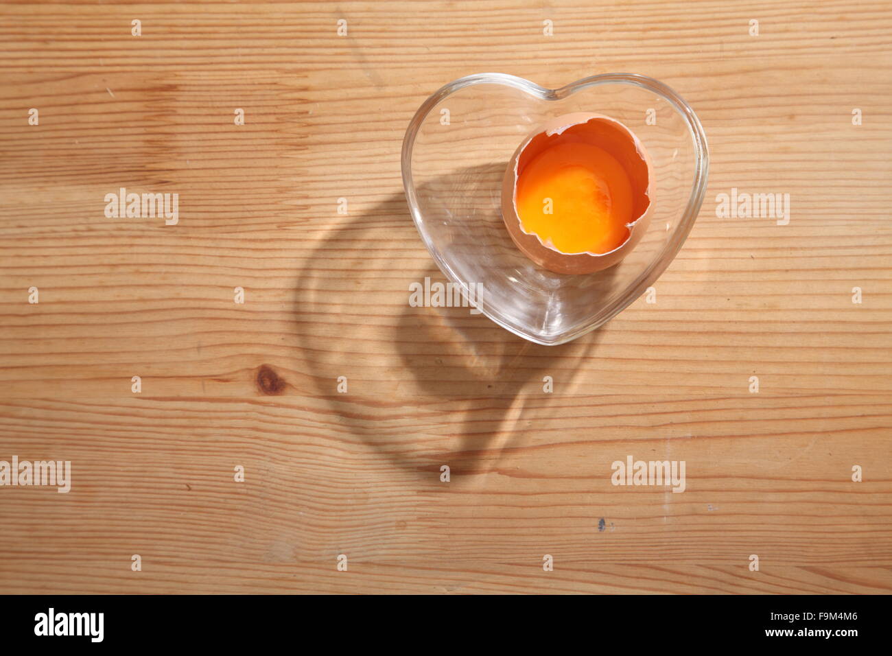 Braunen Eiern in Herz-Form transparent Schüssel auf hölzernen Hintergrund. Stockfoto