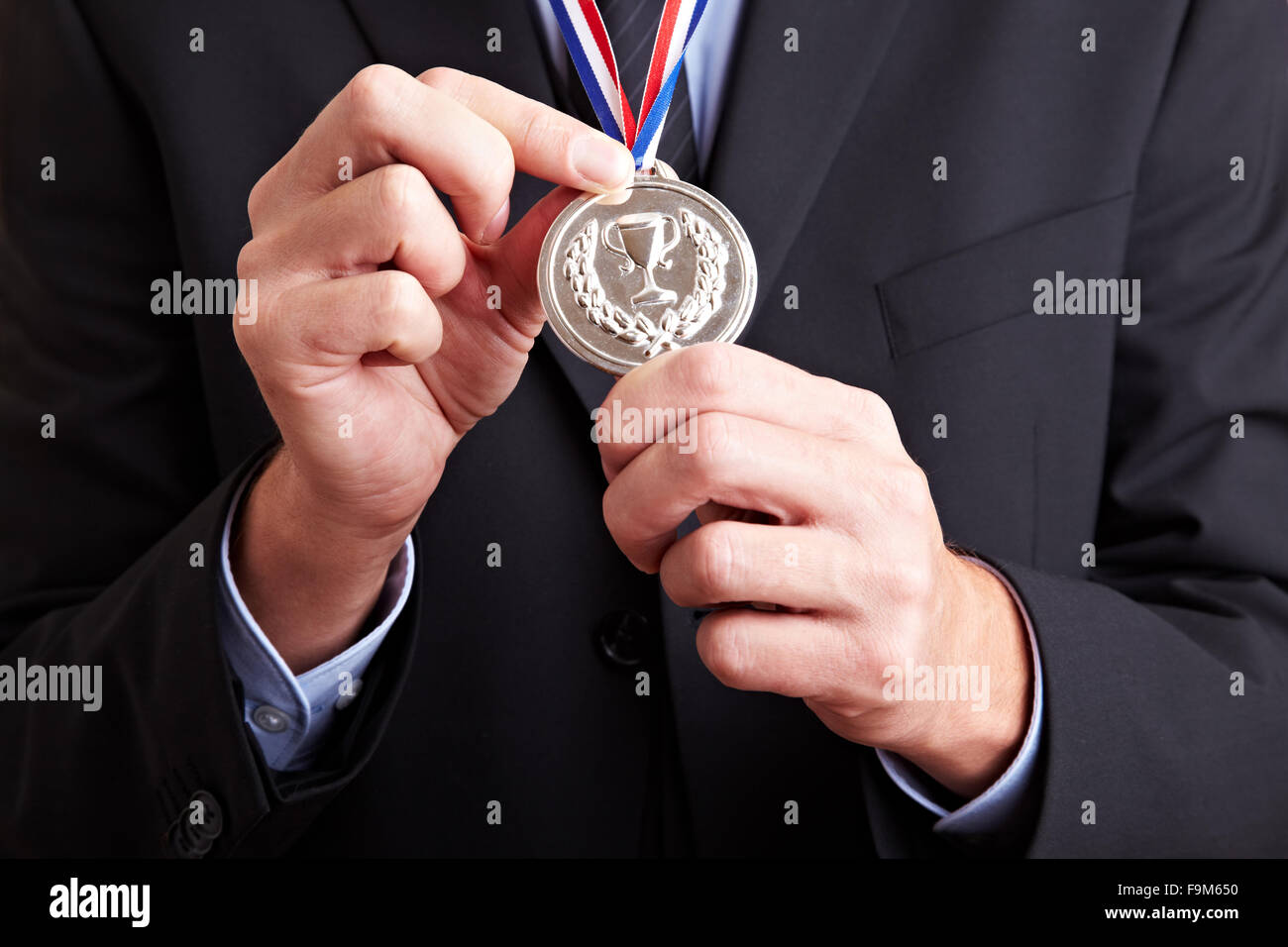 Hände in einem Business-Anzug hält eine Silbermedaille Stockfoto