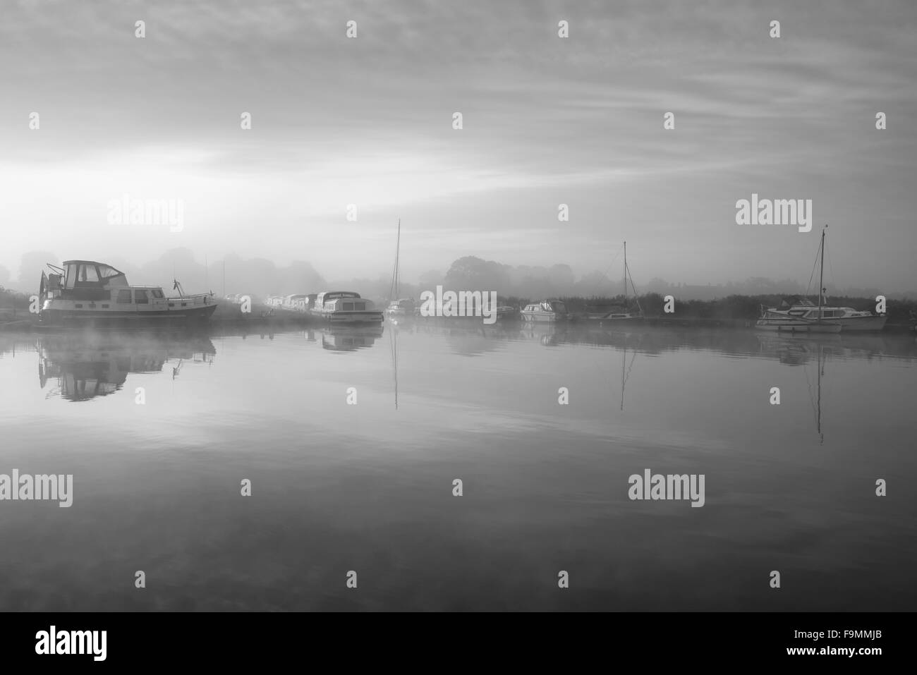 Atemberaubende nebligen Sonnenaufgang über dem ruhigen Flusslandschaft im englischen Landschaft in schwarz / weiß Stockfoto