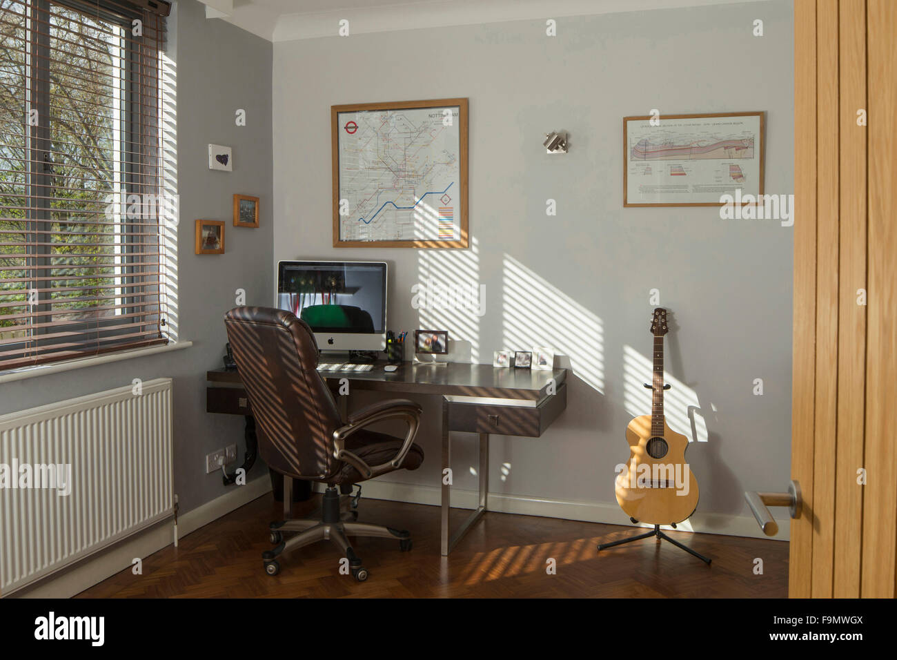 Home-Office-Studie. Eine Gitarre, Computer-Monitor und Tastatur auf dem Schreibtisch. Weiße Wände. Stockfoto