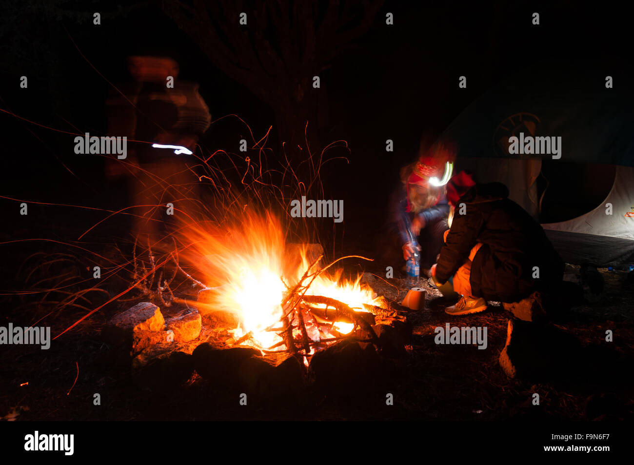 Wanderer versammelten sich rund um ein Lagerfeuer am Abend mit Langzeitbelichtung geschossen Stockfoto