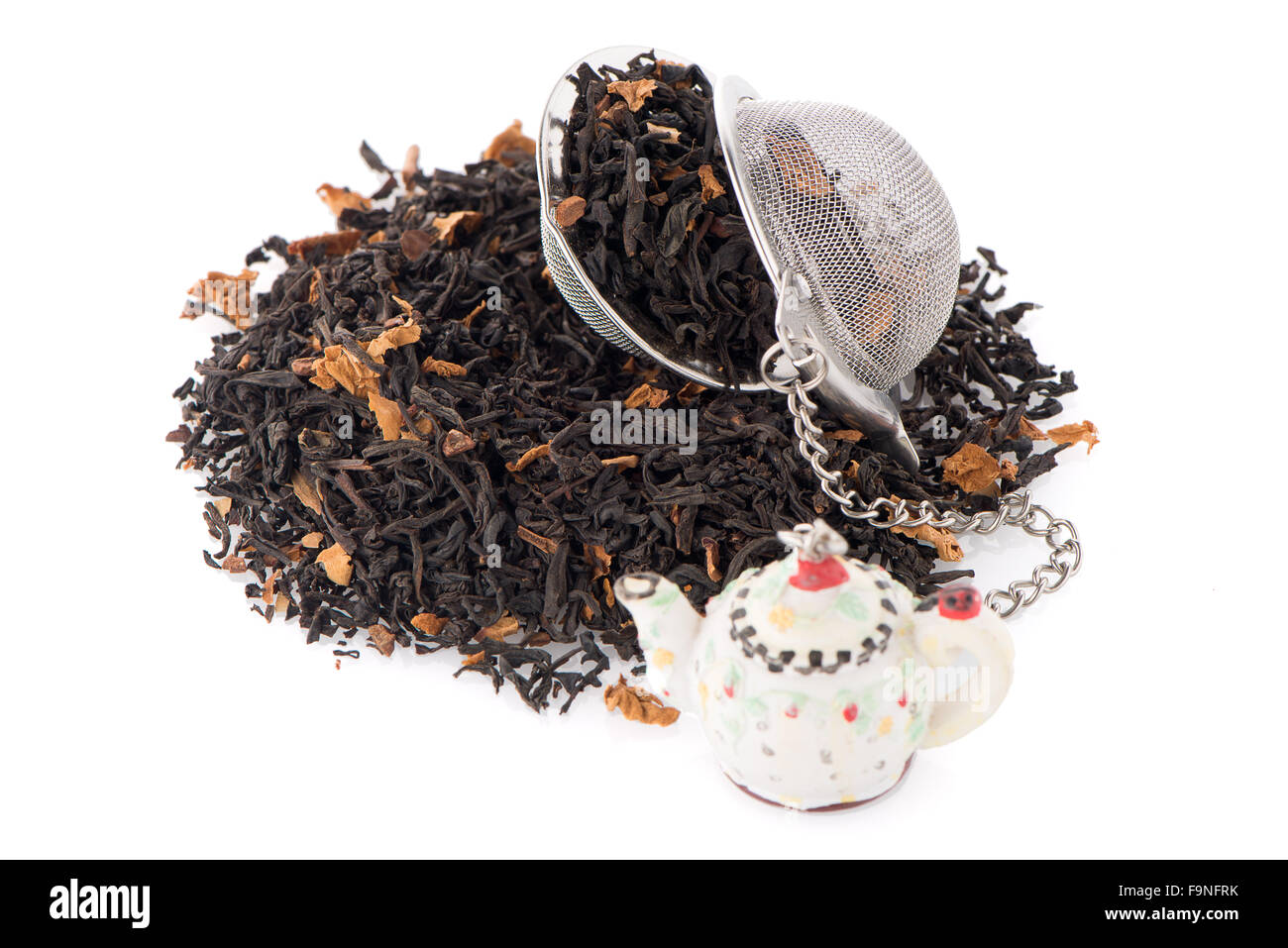 Aromatischer Schwarztee trocken mit Blütenblättern und ein Teesieb auf weißen reflektierenden Hintergrund. Stockfoto