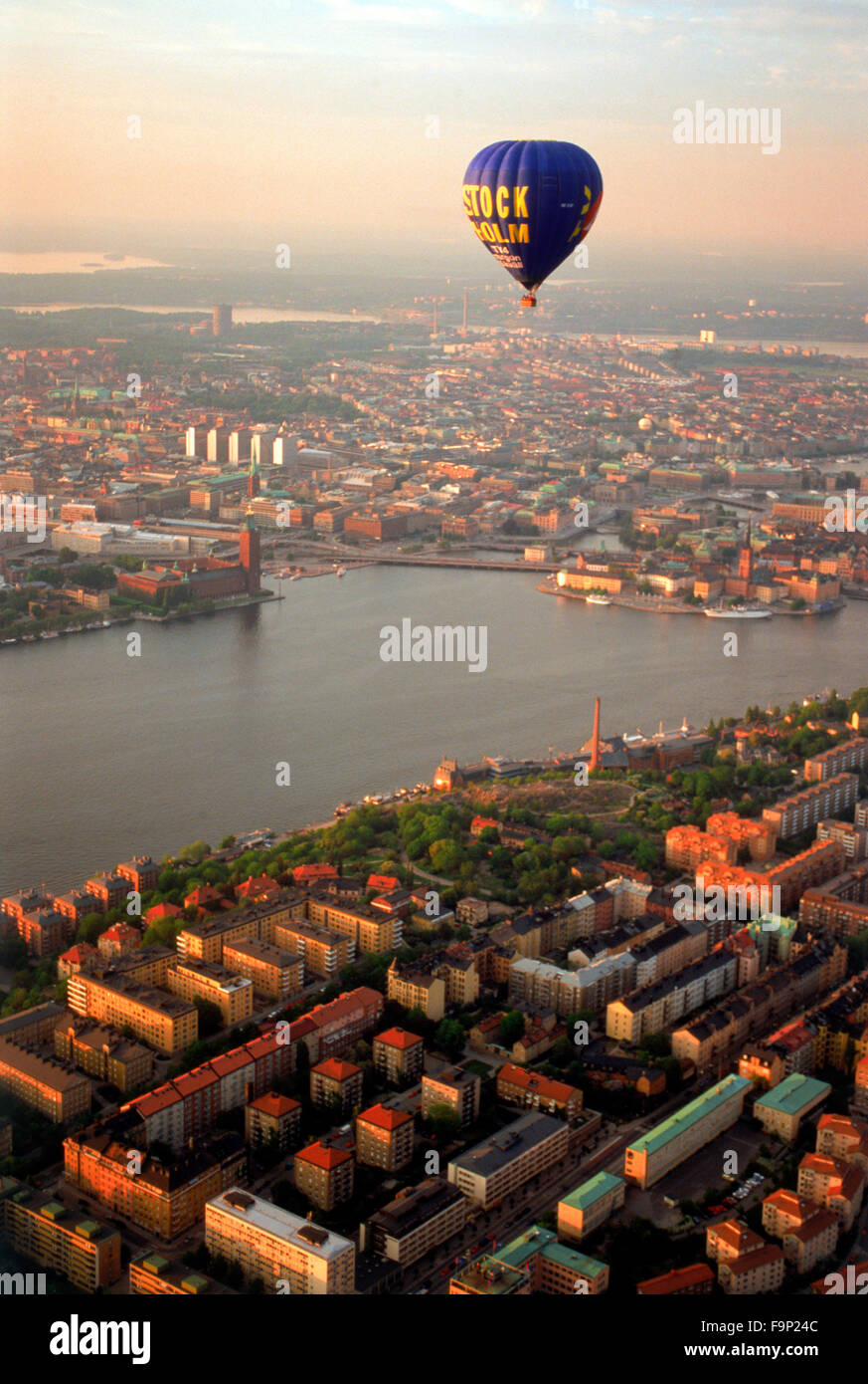 Heißluft-Ballon schwebt über Södermalm und Inseln von Stockholm mit dem Rathaus in Riddarfjarden Gewässern bei Sonnenuntergang Stockfoto