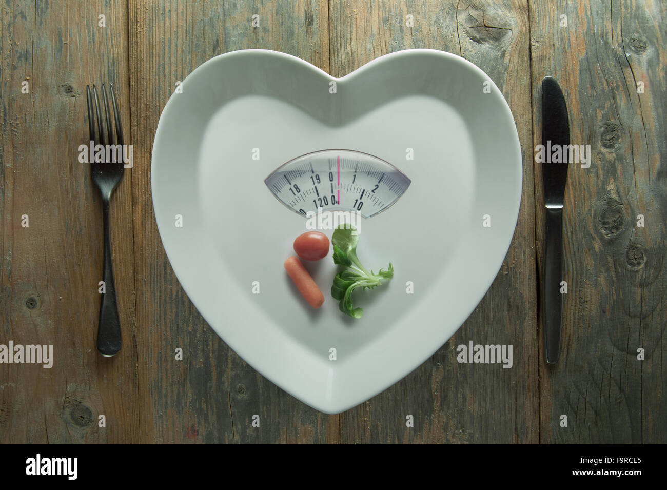 Herz-Form-Platte mit Waage und eine kleine Portion Gemüse Stockfoto