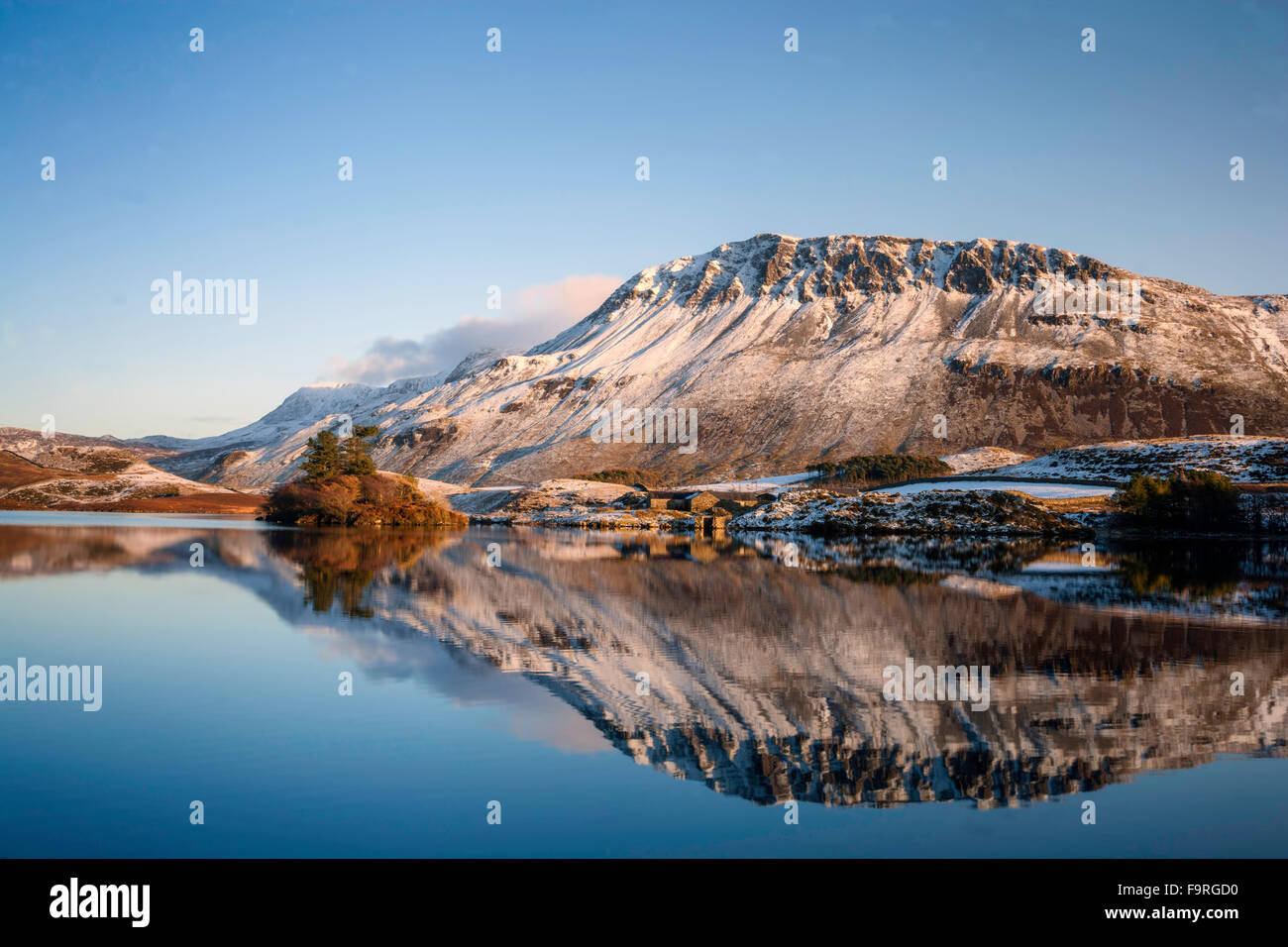 Die Winter tief verschneiten Hänge des Gebirges Cader Idris spiegeln sich im ruhigen Wasser der Cregennen Seen. Stockfoto