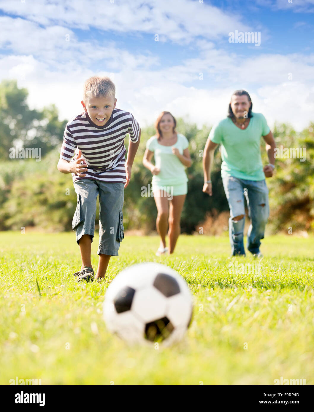 junge Teenager mit den Eltern spielen mit Fußball im Sommerpark Stockfoto