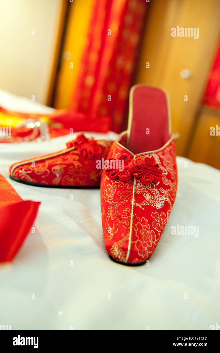 traditionelle chinesische Schuhe auf Bett und Kleid im Hintergrund Stockfoto