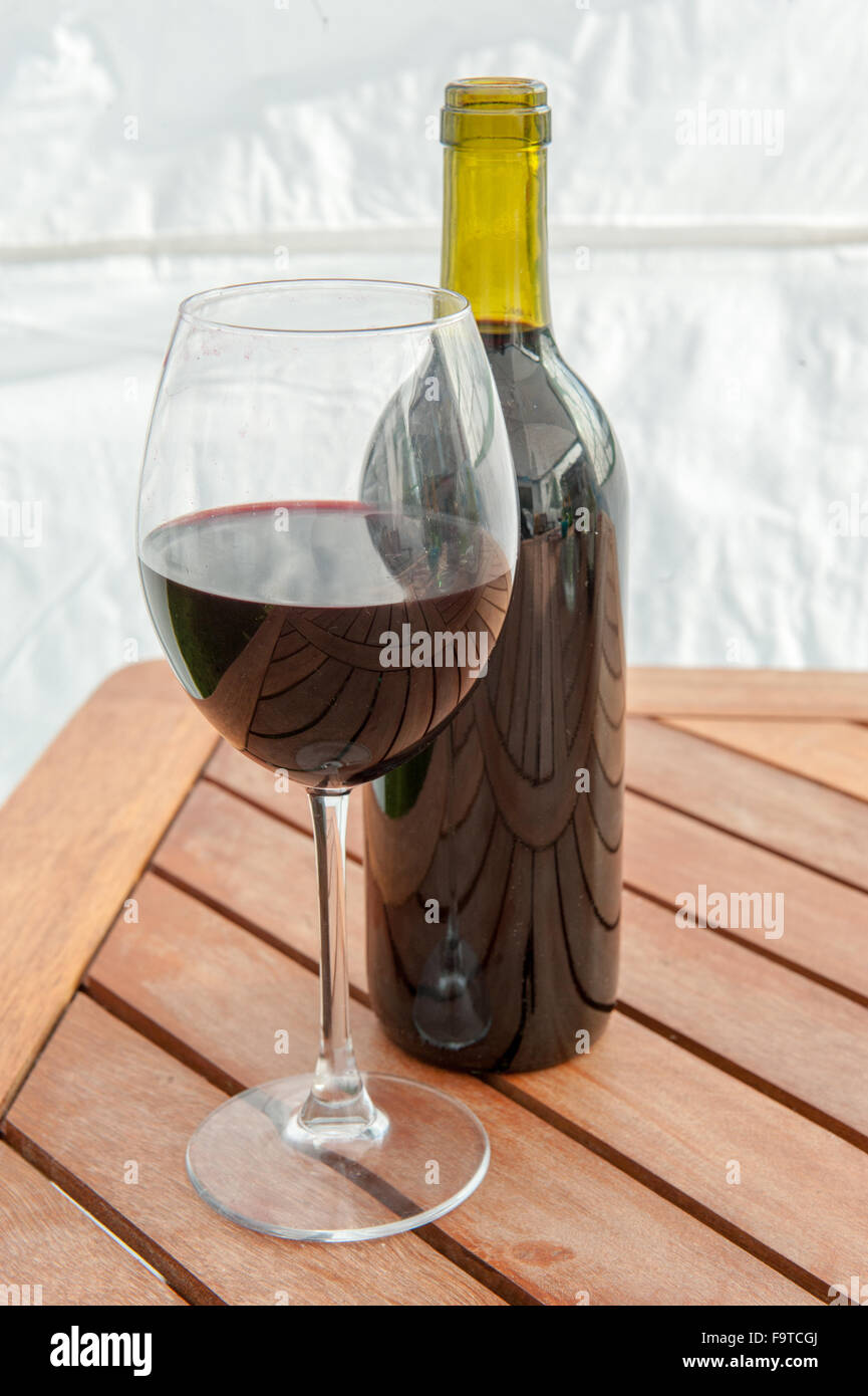 Einzelne Flasche Rotwein und Glas auf Tisch Stockfoto