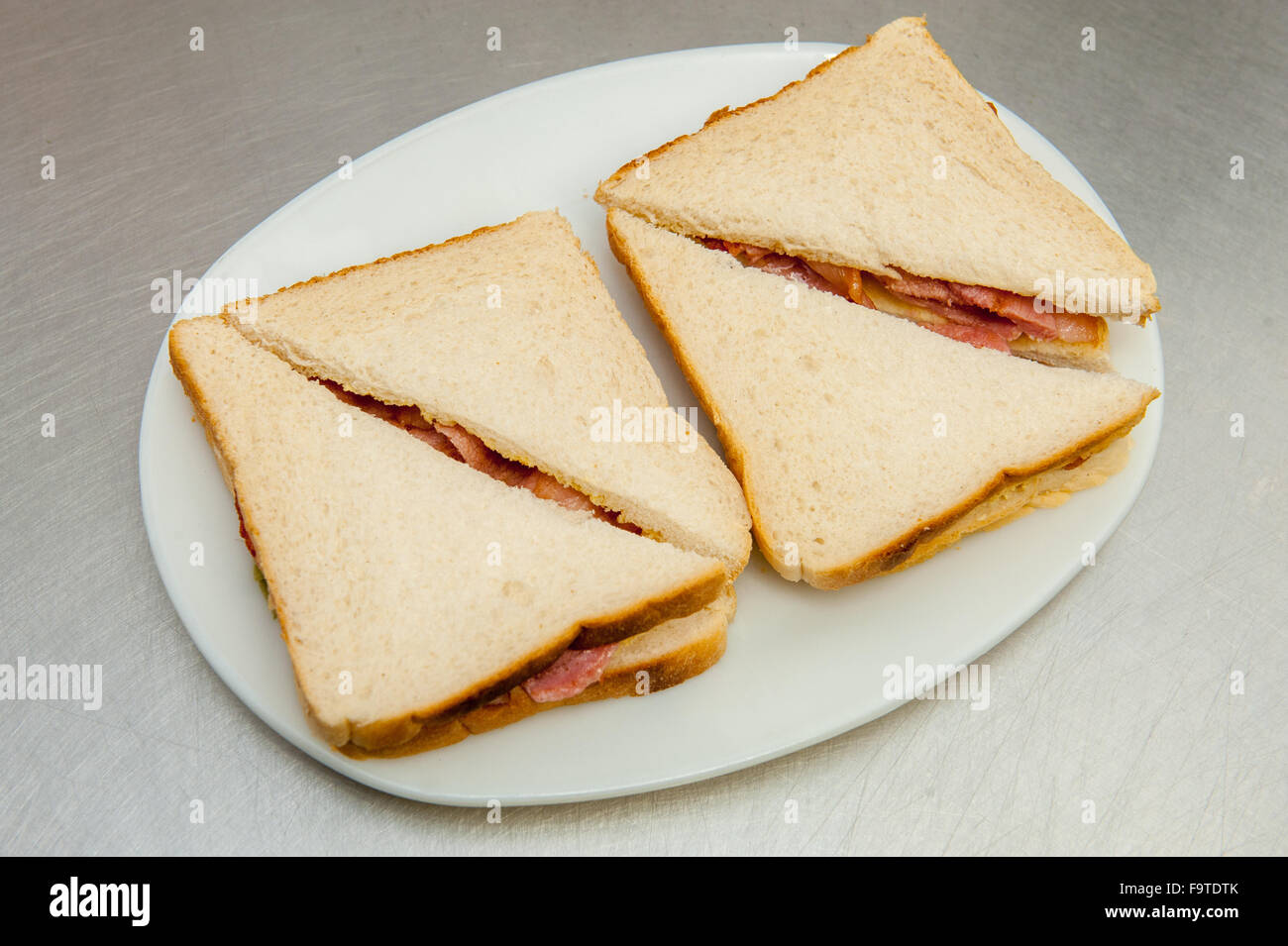 Zwei geschnittene Speck Sandwiches auf einem Teller Stockfoto