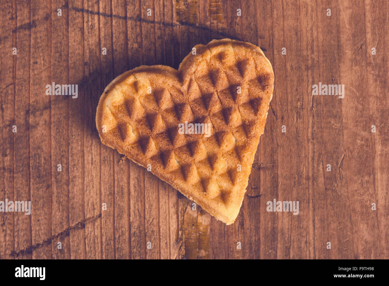 Herzförmige hausgemachte Waffel auf hölzernen Schreibtisch, Retro-getönten, Top Aussicht. Stockfoto