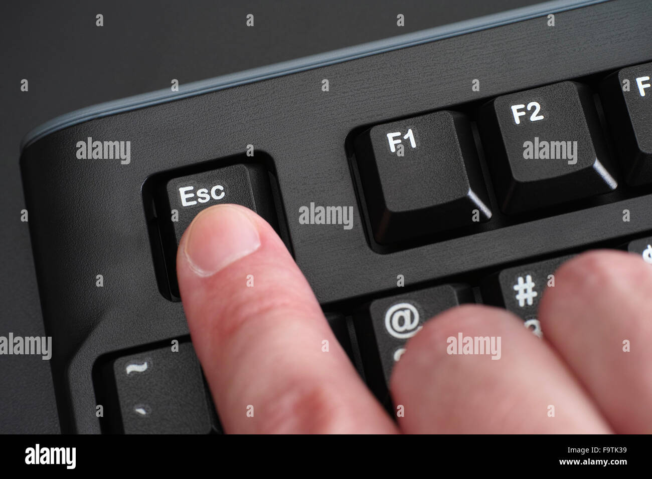 Finger, die Esc-Taste drücken, auf schwarzen Tastatur Stockfoto