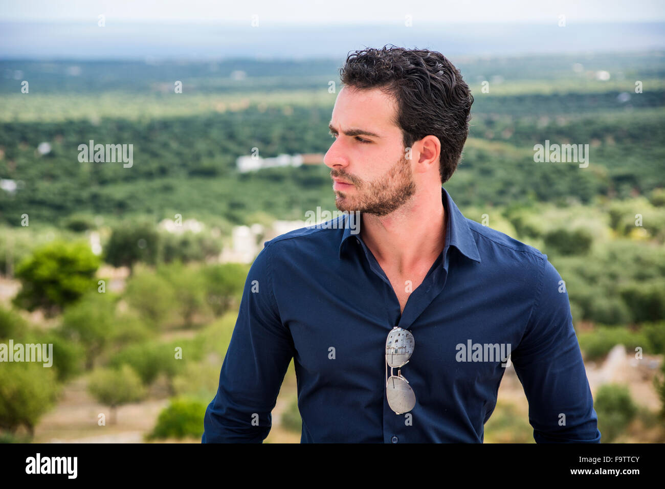 Porträt von eleganten attraktiver junger Mann mit lockigem Haar gegen der Küste stehen und blickte auf eine Seite mit ernstem Gesicht Stockfoto