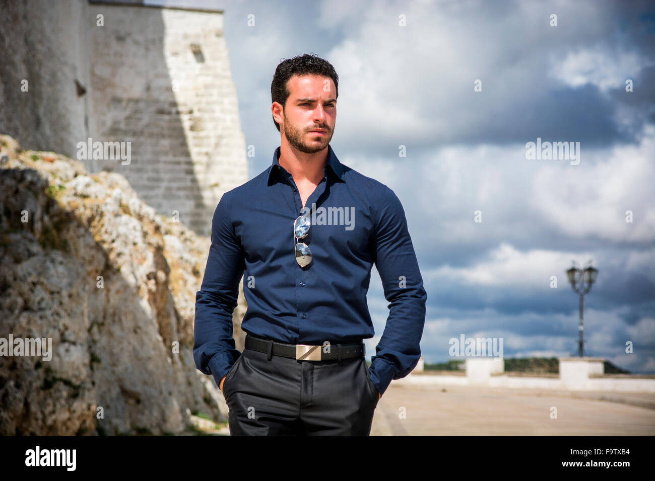 Porträt von eleganten attraktiver junger Mann mit lockigem Haar gegen der Küste stehen und blickte auf eine Seite mit ernstem Gesicht Stockfoto