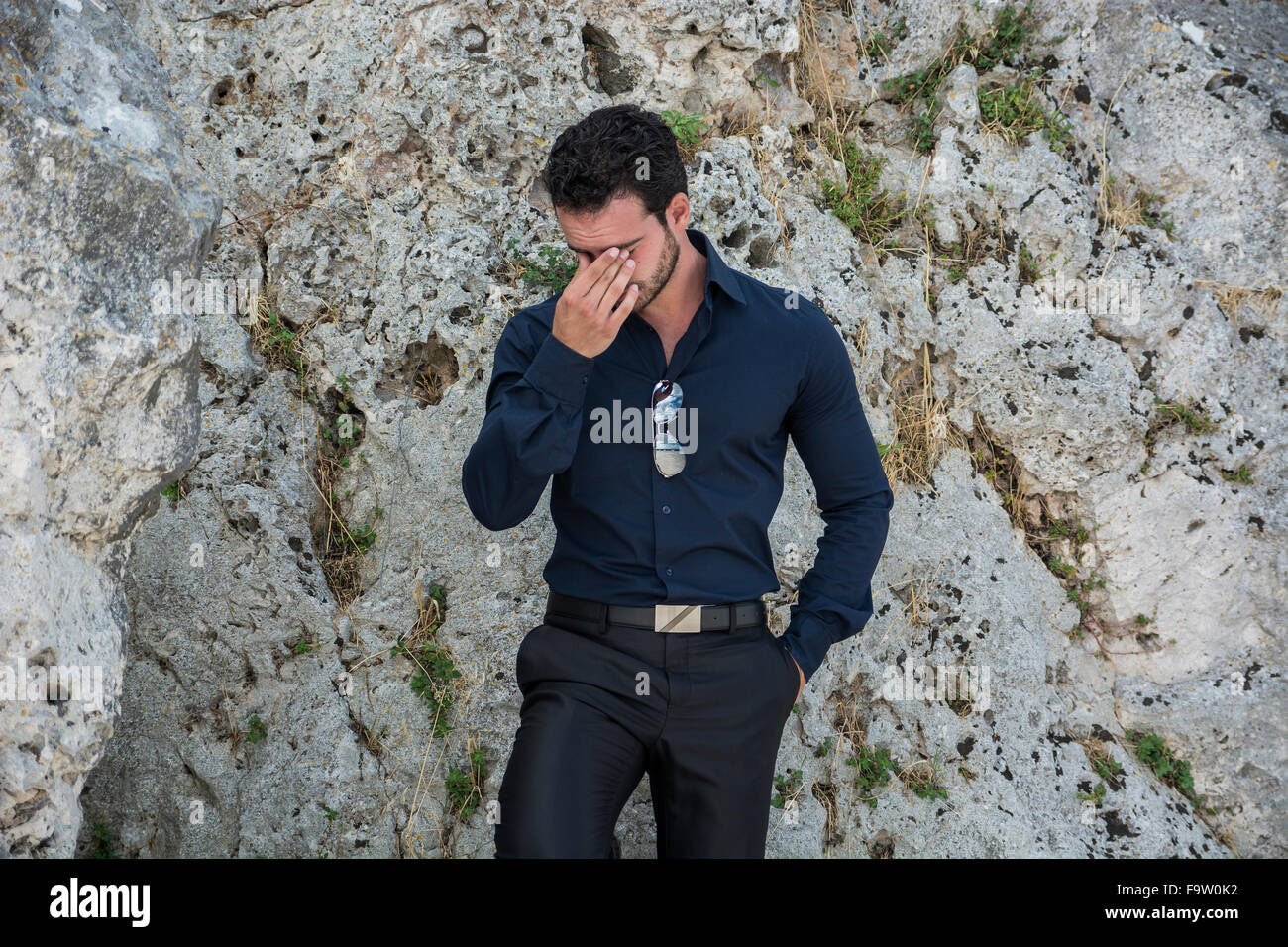 Eine halbe Stelle erschossen eines wunderschönen jungen Geschäftsmann gegen Boulder mit Händen in den Taschen und in die Kamera schaut. Stockfoto