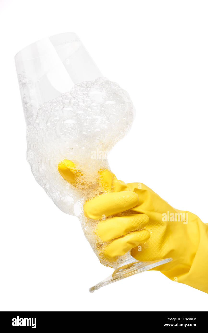 Nahaufnahme des weiblichen Hand in gelben schützende Gummihandschuh hält sauber transparentes Glas Wein im Schaum vor weißem Hintergrund. Stockfoto