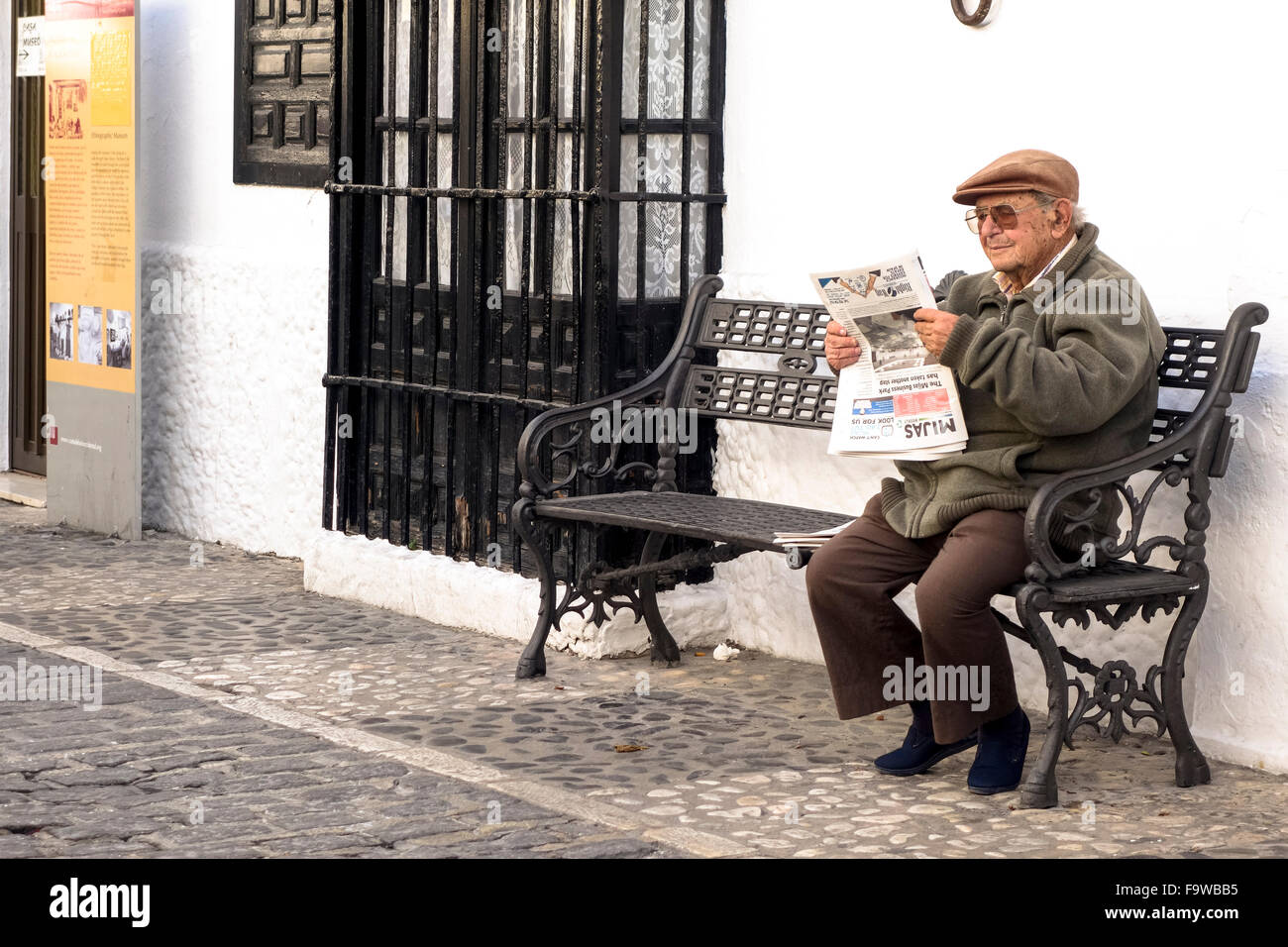 Senior spanischen Mann liest Zeitung auf Bank im andalusischen Dorfes Mijas, Andalusien, Spanien. Stockfoto