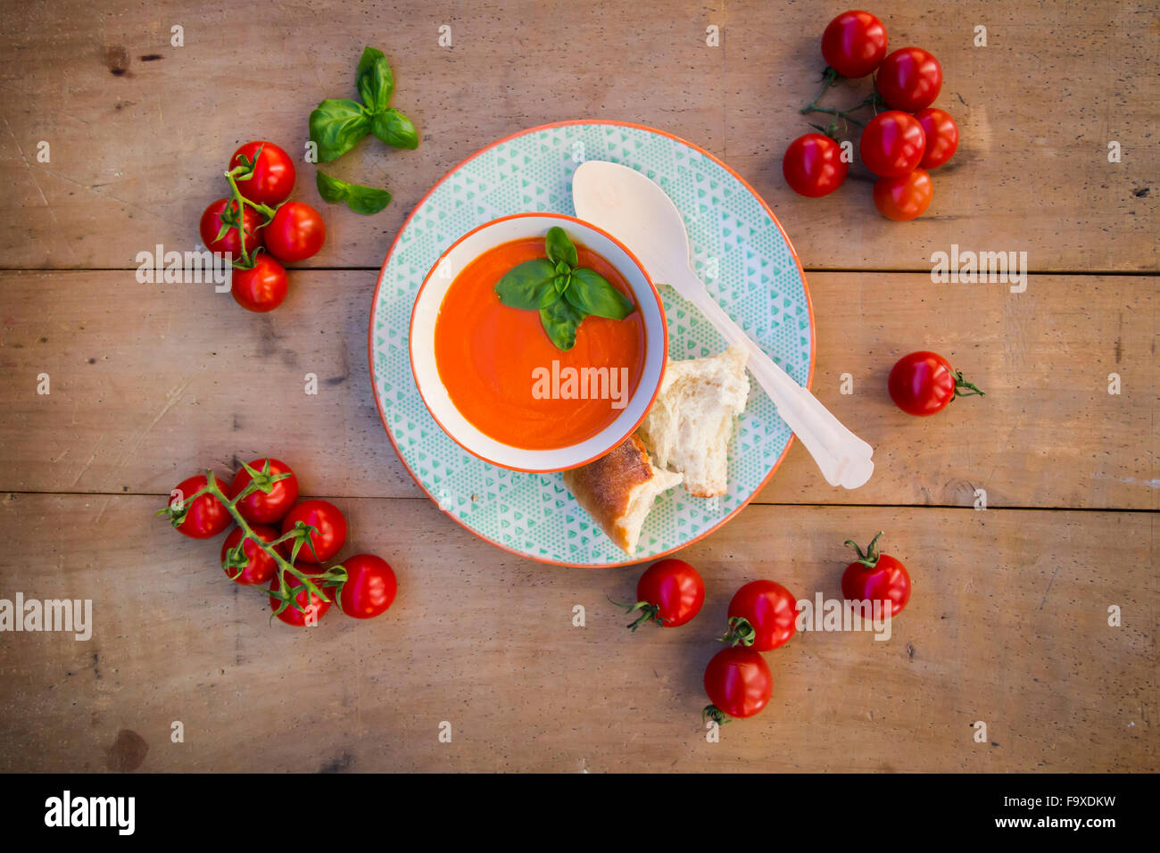 Schüssel mit Tomatencremesuppe garniert mit Basilikum und einem recyclebaren Holzlöffel Stockfoto