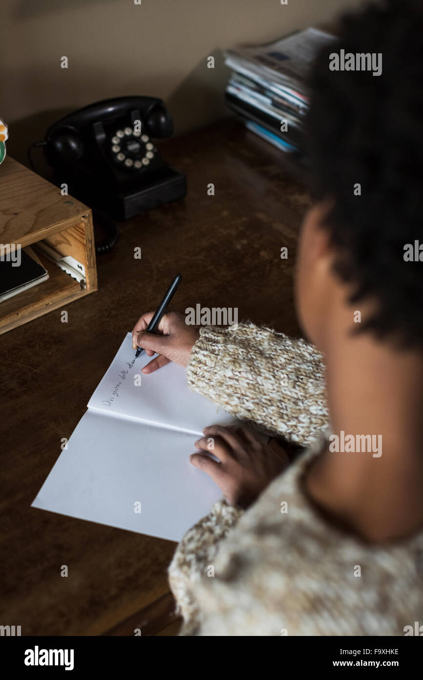 Junge Frau am Schreibtisch schreiben in notebook Stockfoto