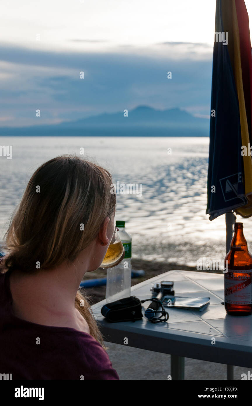 Frau mit einem Drink am Strand Stockfoto