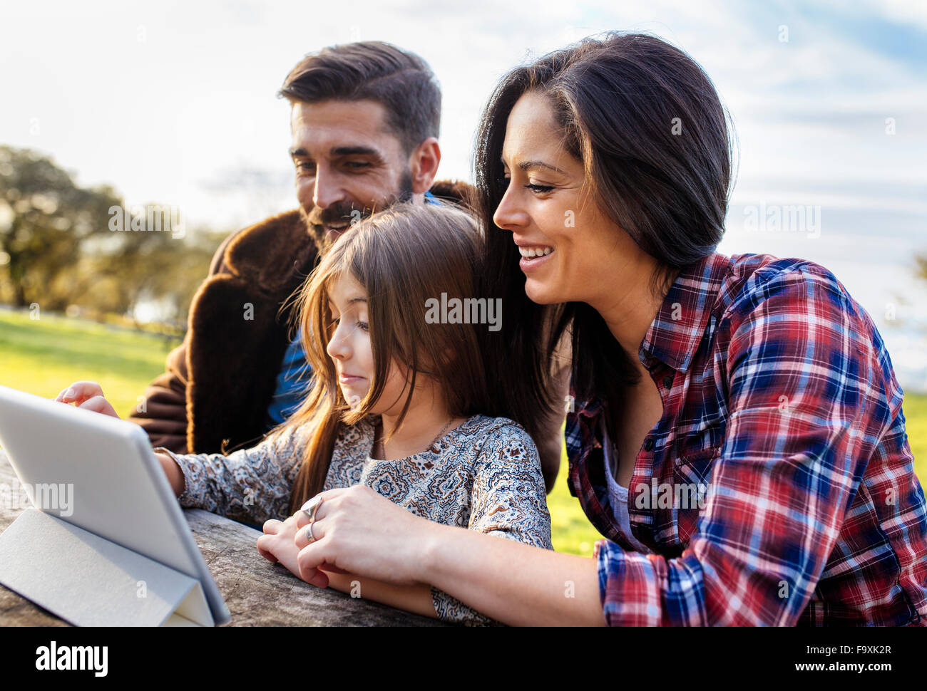 Glückliche Eltern mit Tochter mit digital-Tablette im freien Stockfoto